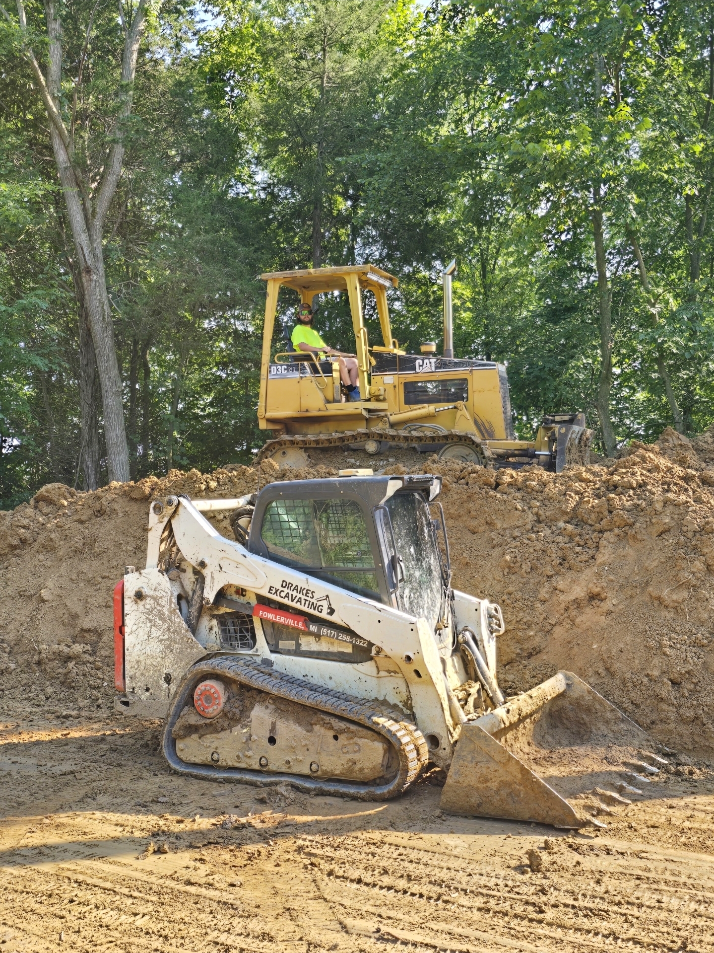 Drake's Excavating equipment on a job site — CAT dozer and Bobcat skid steer in action